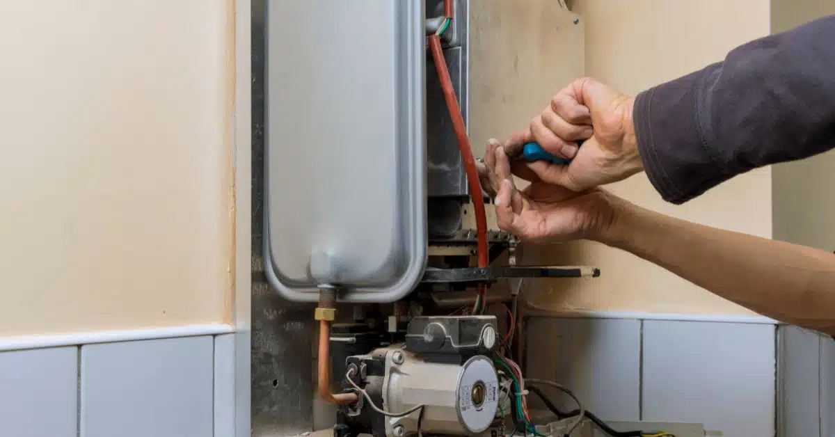 Repairman fixing a gas water heater with a screwdriver