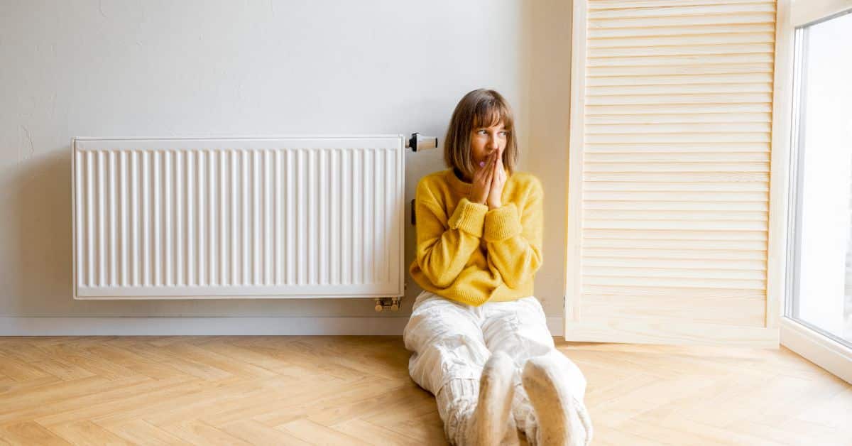 power flush - Cold lady sitting next to a radiator
