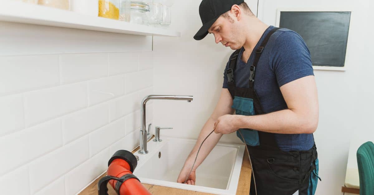 Plumber using an auger to unblock a sink