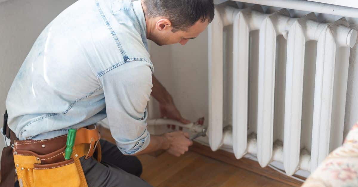 power flush cost - Plumber unscrewing radiator pipe