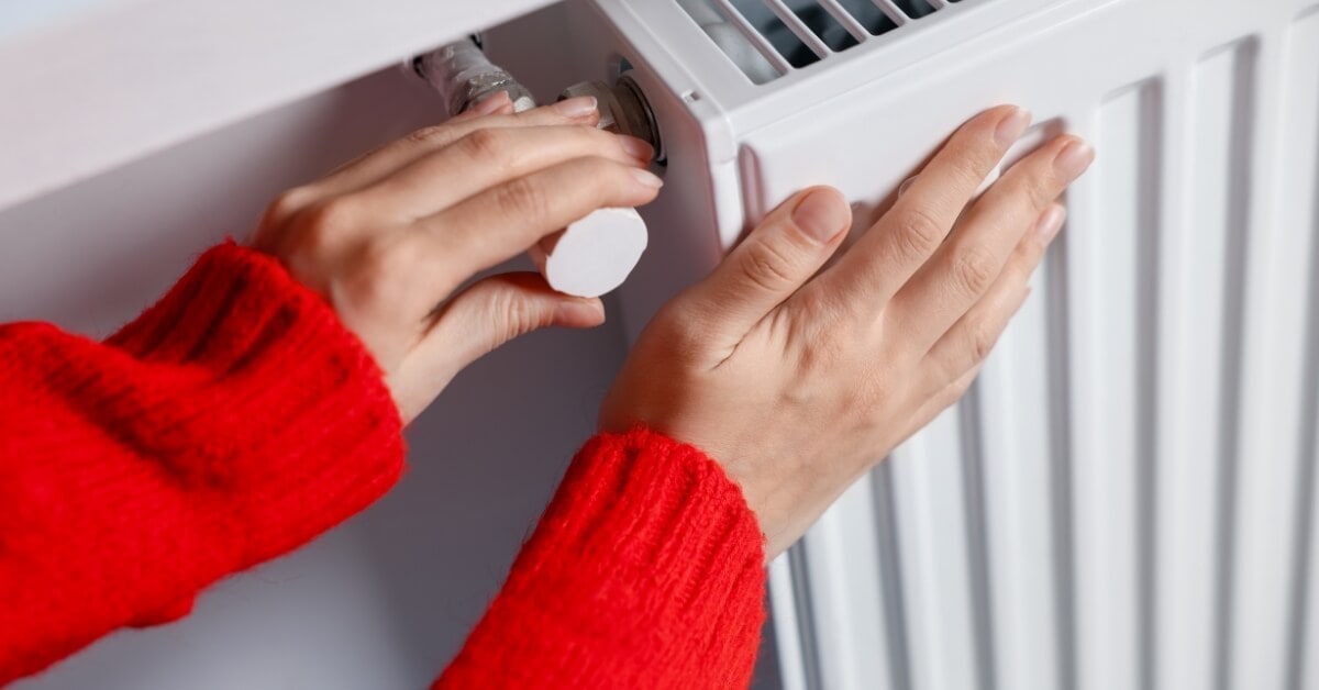 Lady with a red jersey on putting her hand on a radiator to check the heat