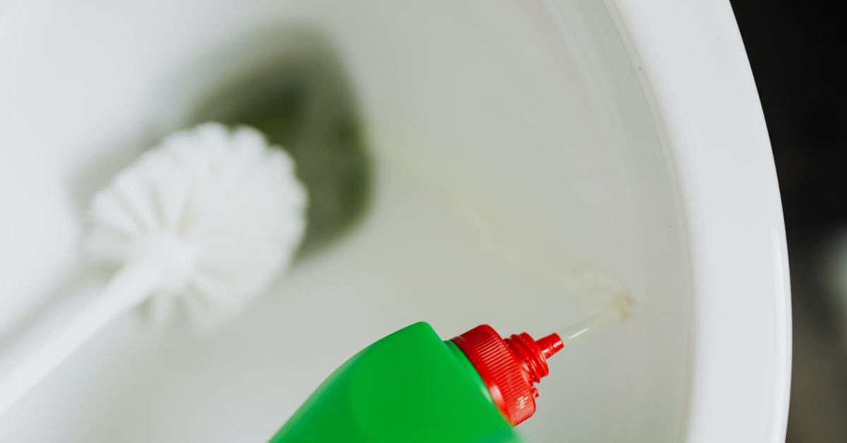 Cleaning a toilet with toilet cleaner and scrubbing brush