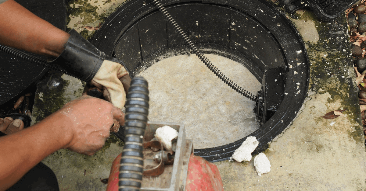 Grease Trap Cleaning - A Plumber Professionally cleaning a grease trap