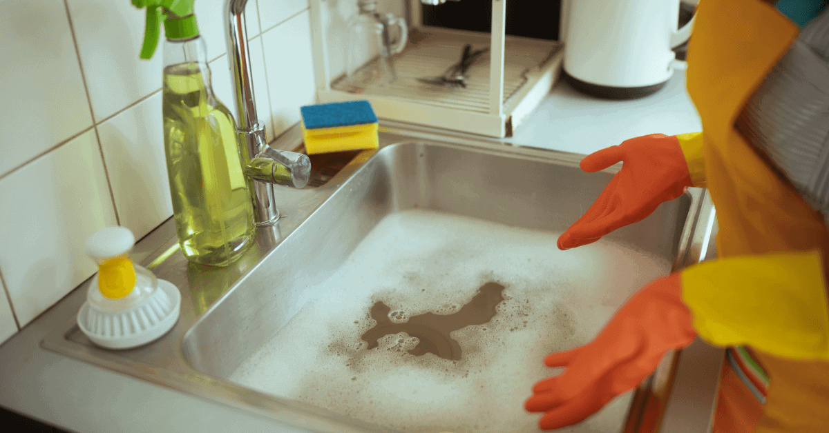 Homeowner using hot water and cleaning detergent to break grease buildup in drain pipes