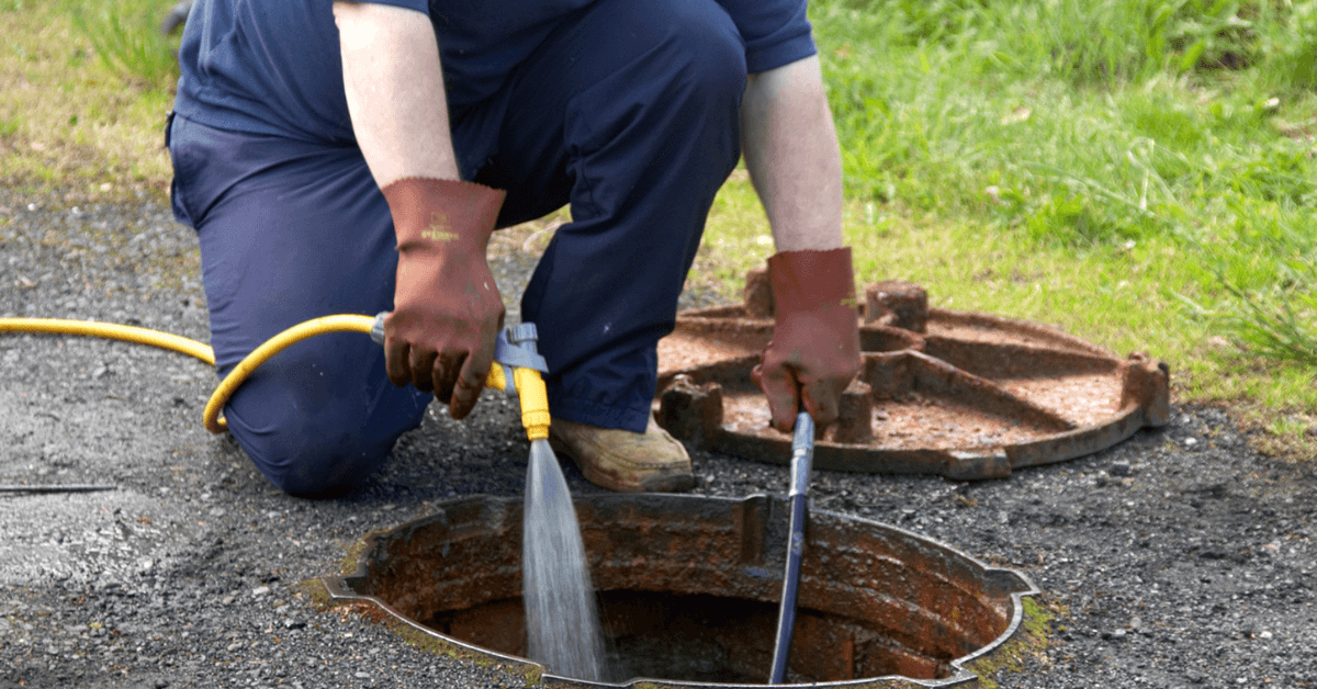 A plumber using a High-water pressured hose to unblock storm drain 