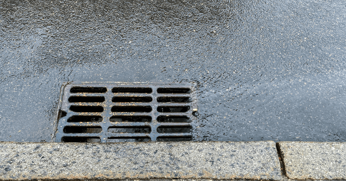 Roadside surface water drain collecting rainwater along a street curb 