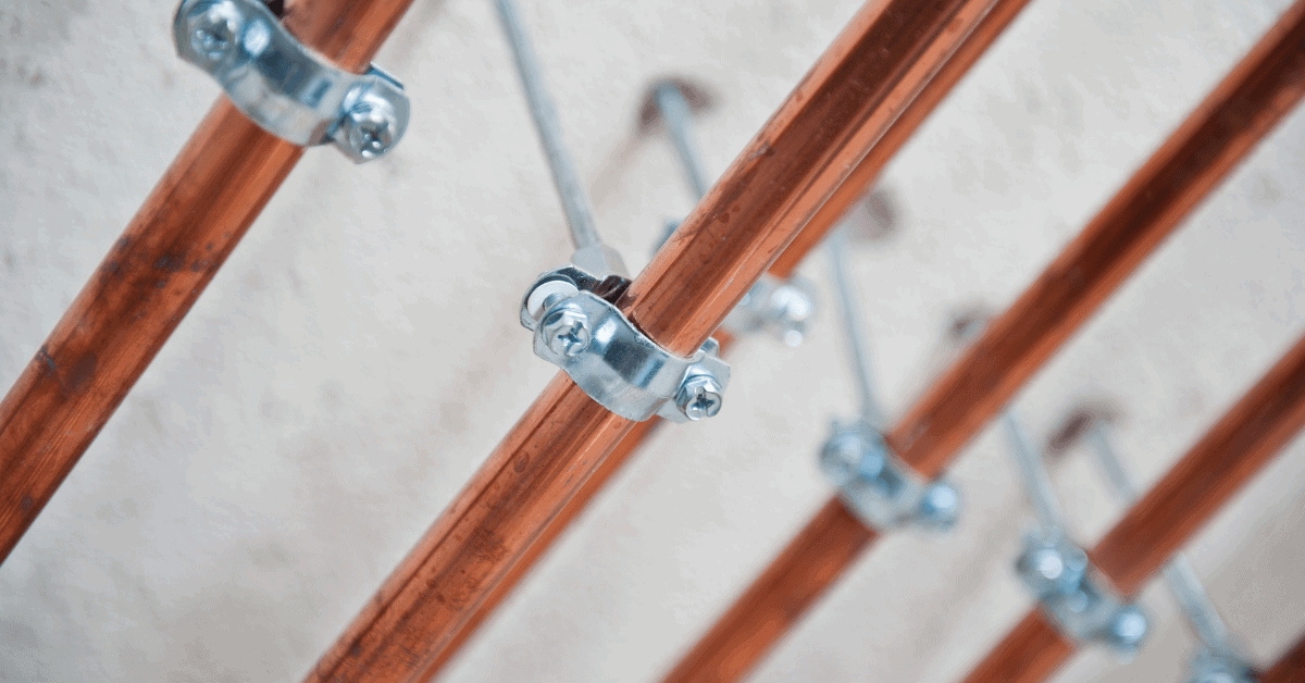 Exposed copper water pipes secured with metal pipe clips 