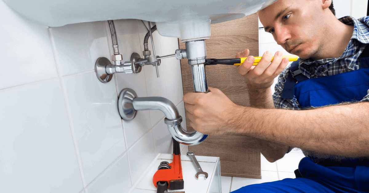 Plumber working on kitchen sink plumbing connections 